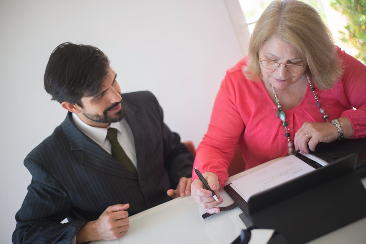 Orange County senior woman signing Medi-Medi plan enrollment paperwork with a benefits counselor