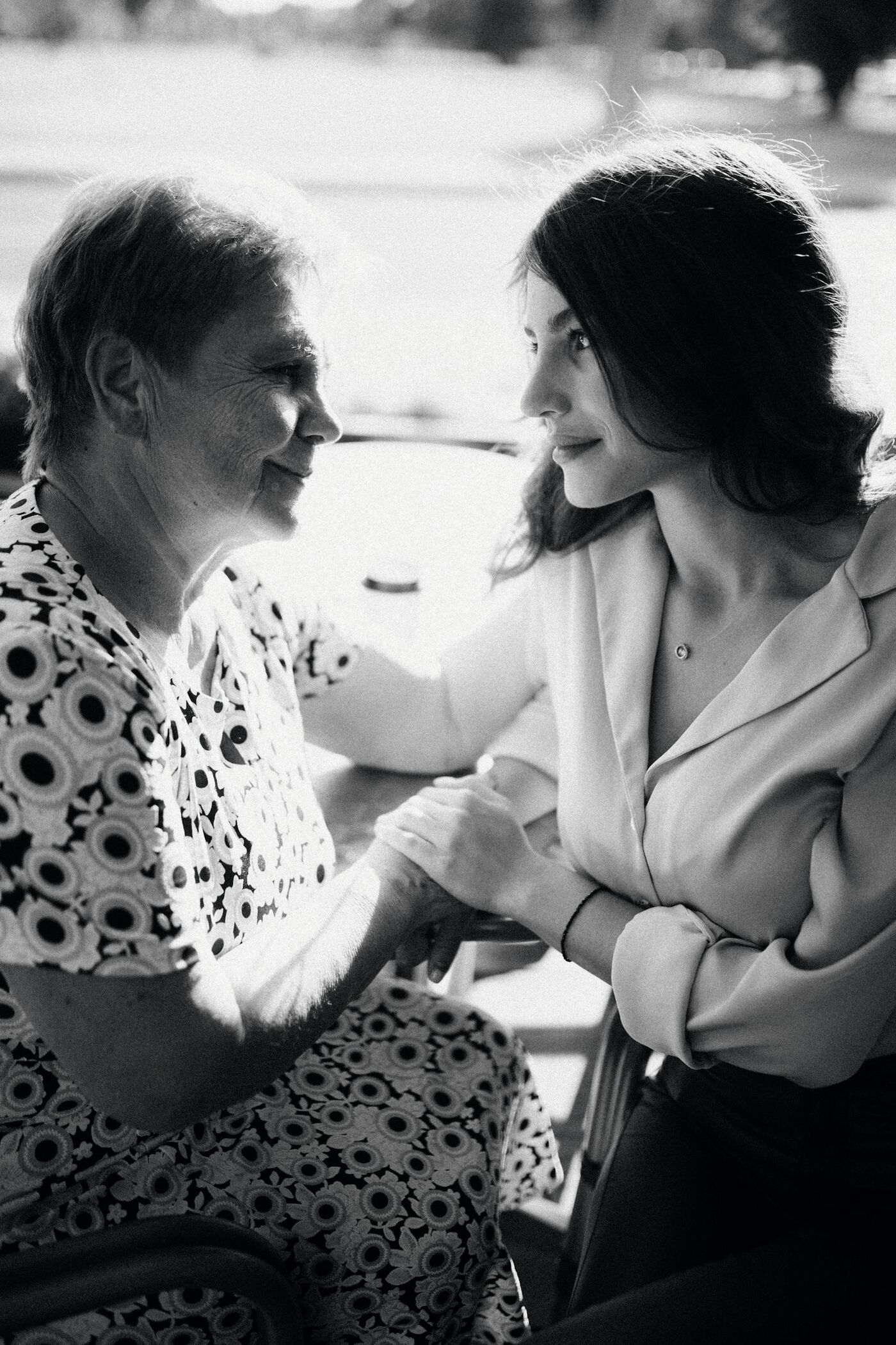 Senior mother and adult daughter holding hands in a tender intimate portrait
