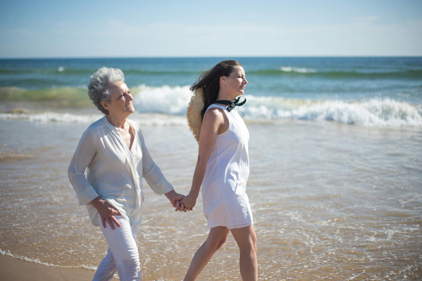 Adult daughter walking and holding hands with her senior mother in a park setting