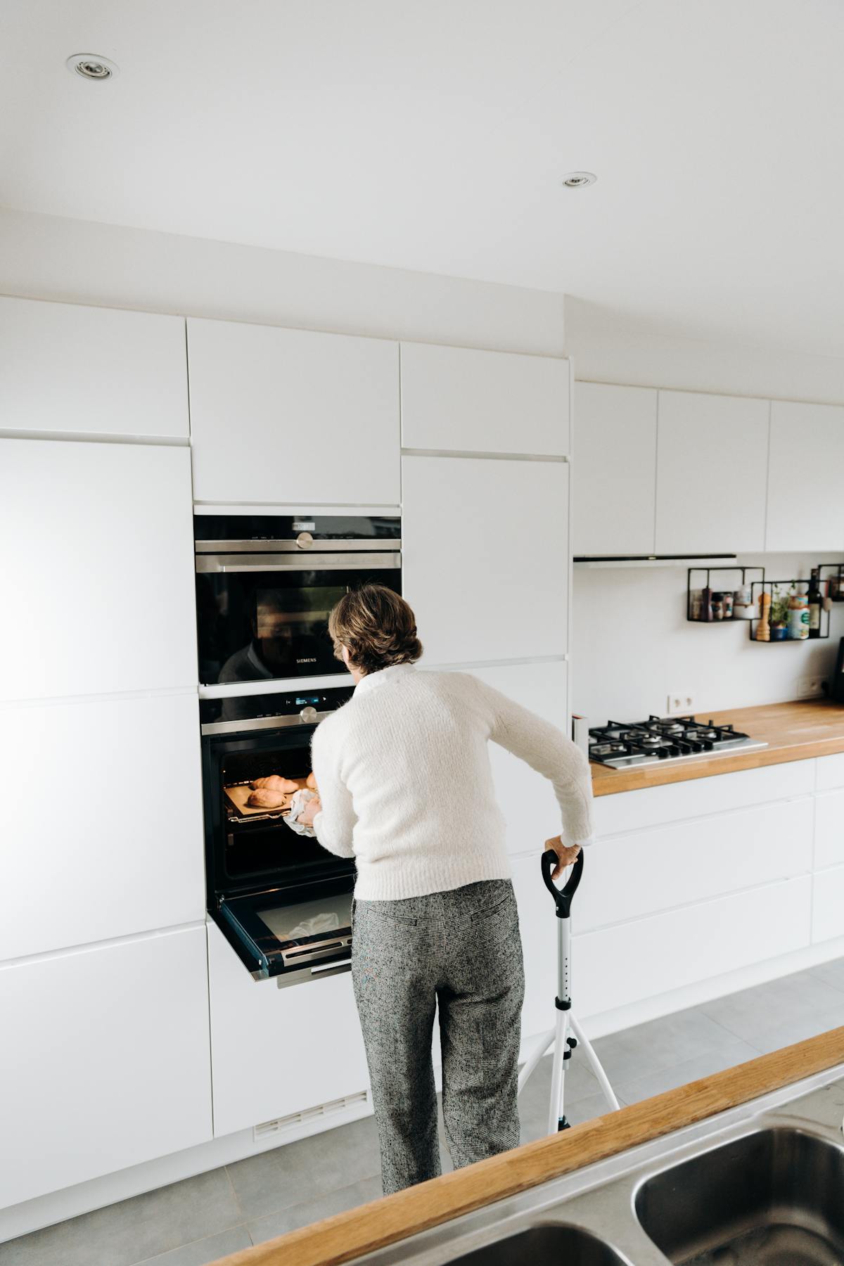 Orange County senior woman cooking independently in her kitchen with the help of a walking aid