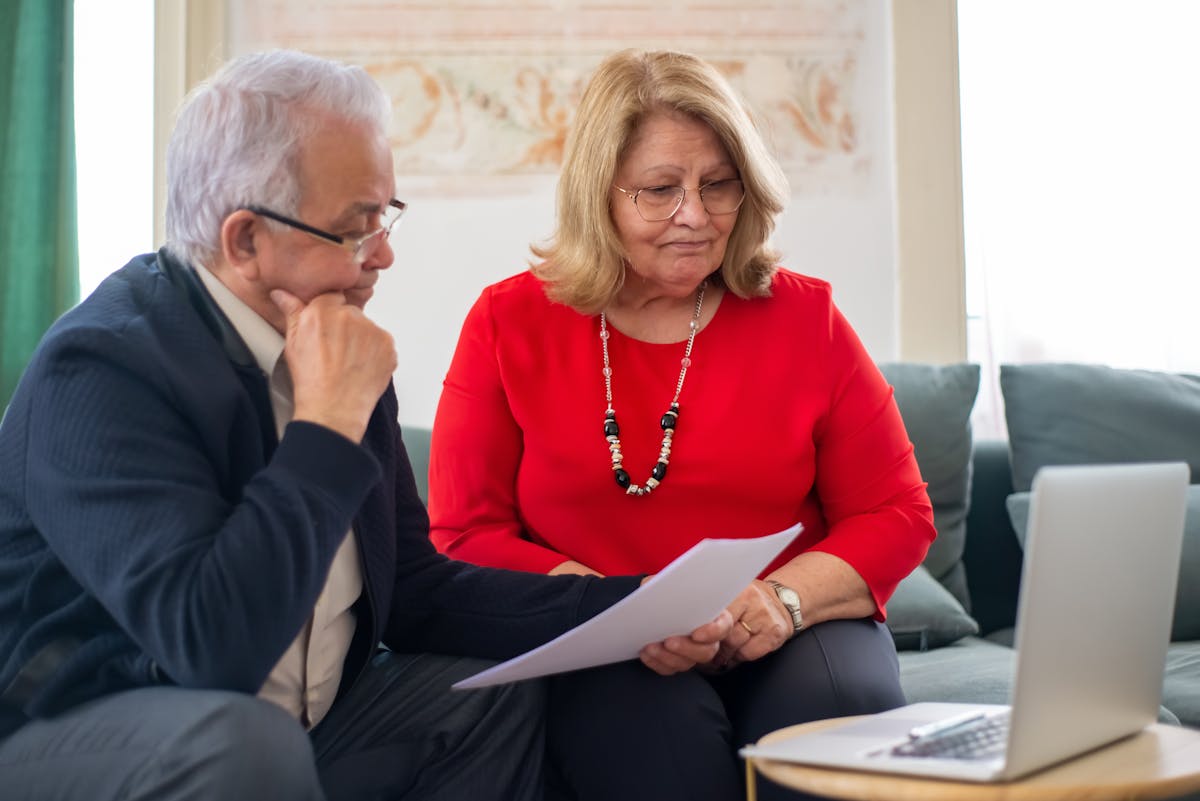 Senior Orange County couple reviewing home repair grant application paperwork together at their kitchen table