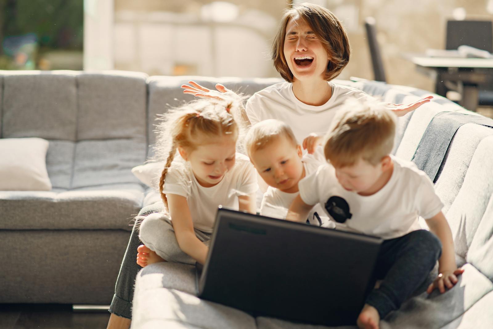 Overwhelmed working mother juggling laptop and caregiving responsibilities in Orange County