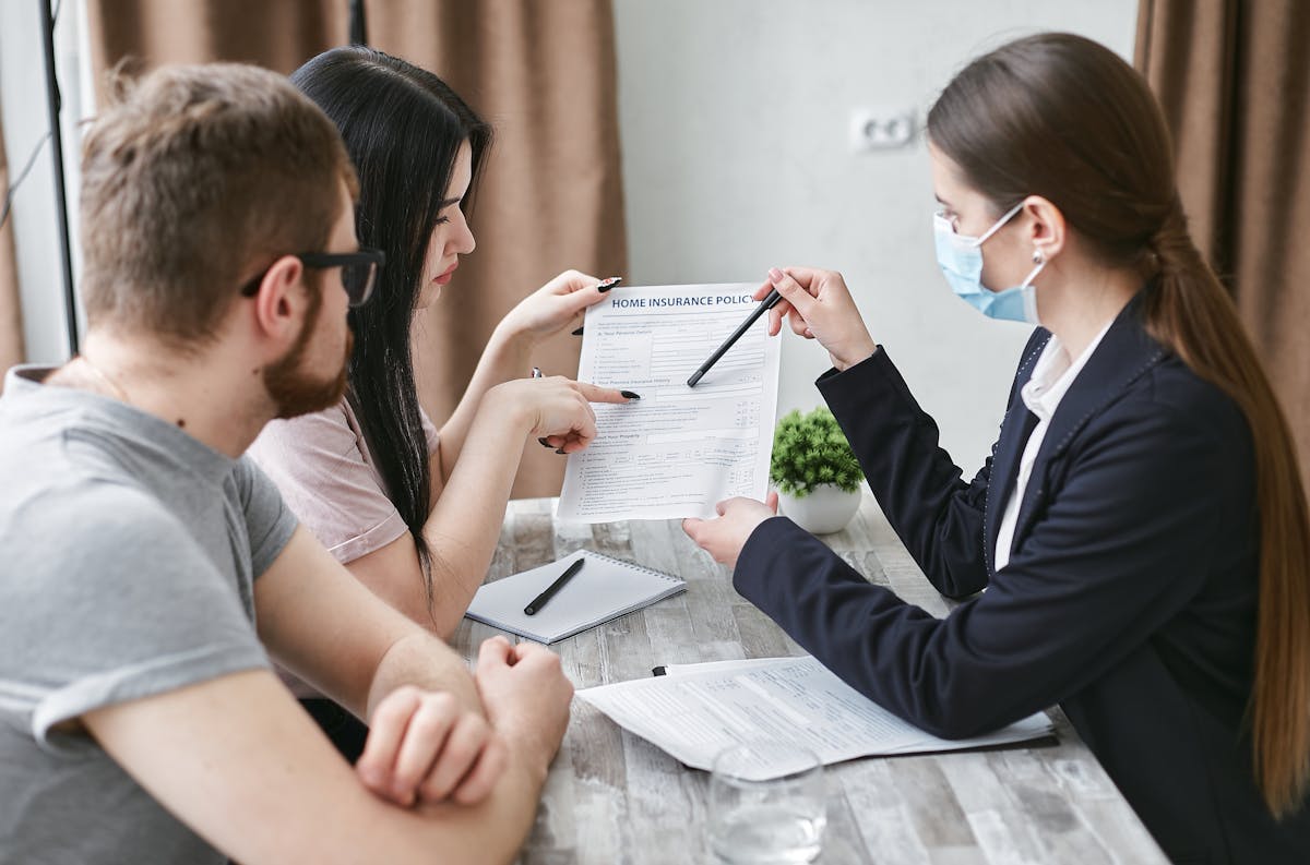 Three adults reviewing health insurance enrollment paperwork at a meeting table in Orange County