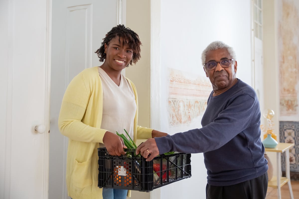 Caregiver delivering food to elderly man at home — CalAIM homemaker services in Orange County