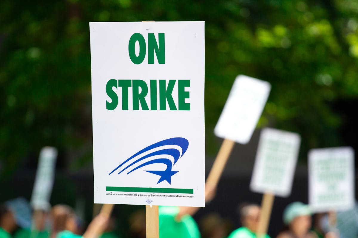 Labor workers holding rally signs at a labor organizing event — OC IHSS caregiver wage dispute 2026