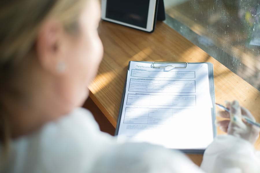 Woman carefully filling out IHSS application form at sunny desk