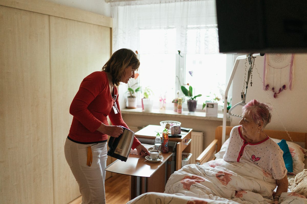 In-home caregiver serving tea to Orange County senior - private home care to offset Medicare Part B 2026 costs