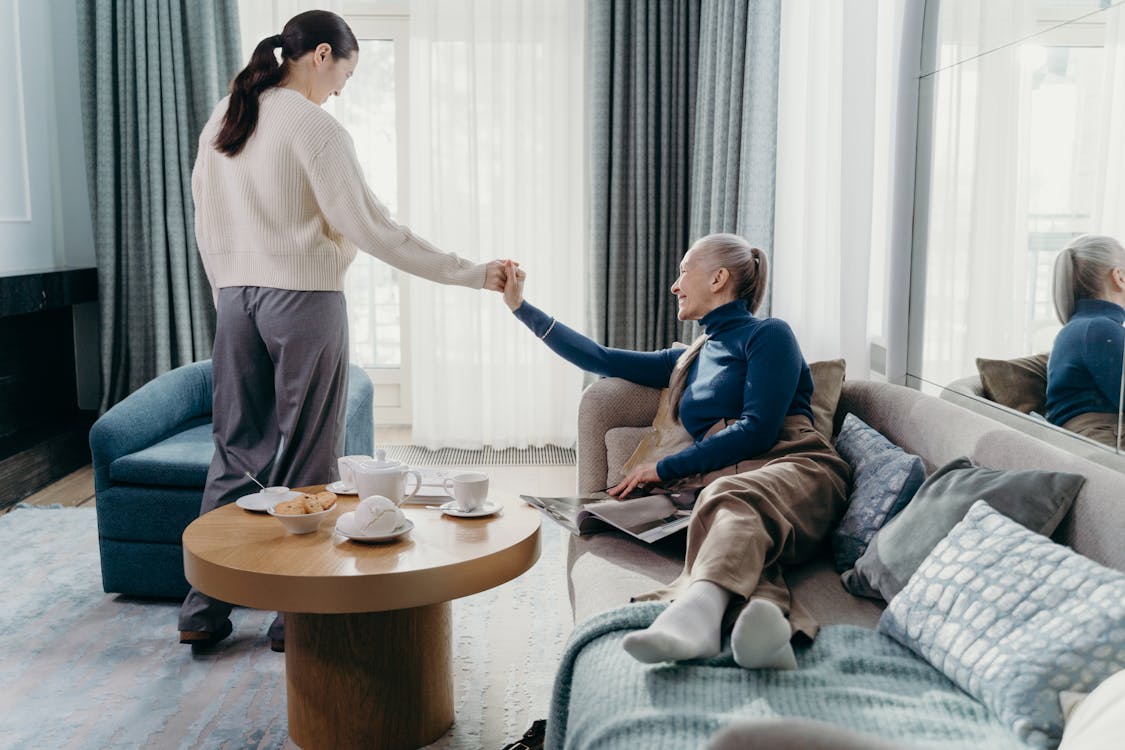 Senior woman and adult daughter relaxing together at home in a cozy living room