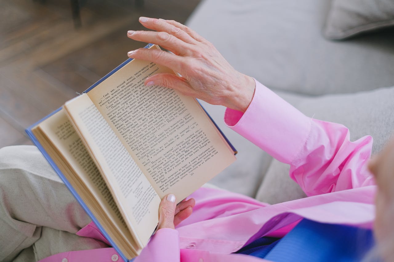 Older woman reading a book on a sofa at home