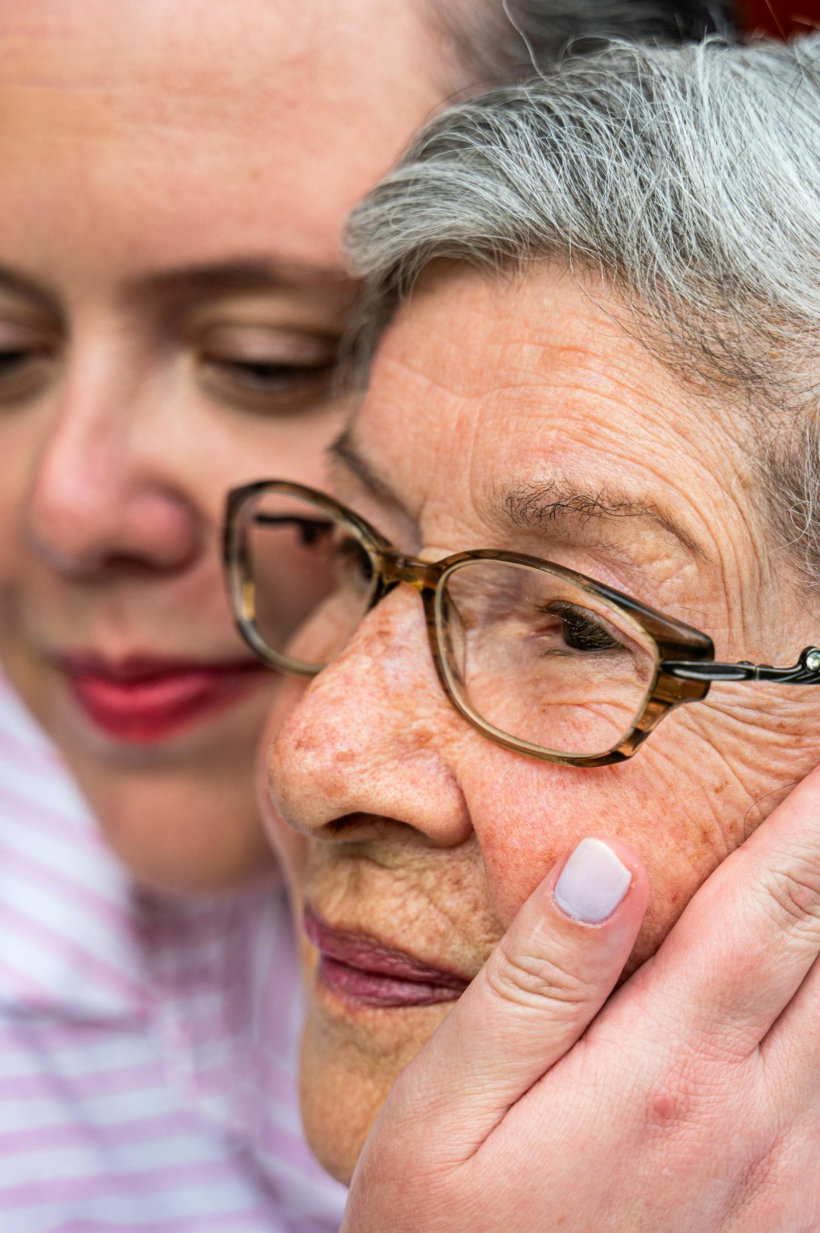 Adult woman holding hands with senior woman during a quiet at-home care visit