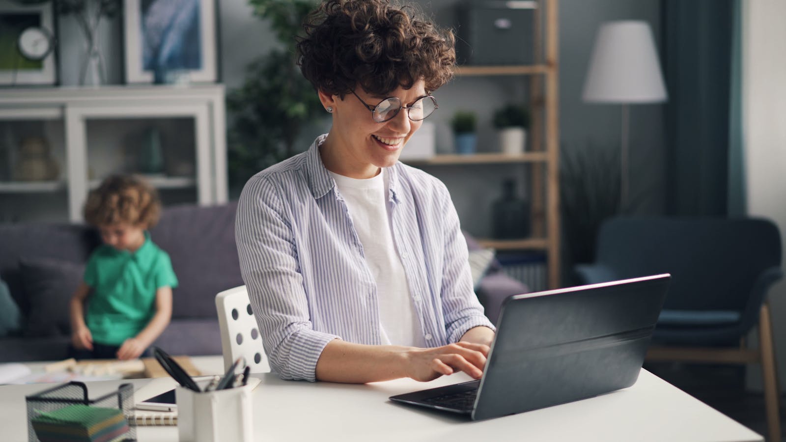 Working caregiver multitasking on laptop at home with family responsibilities