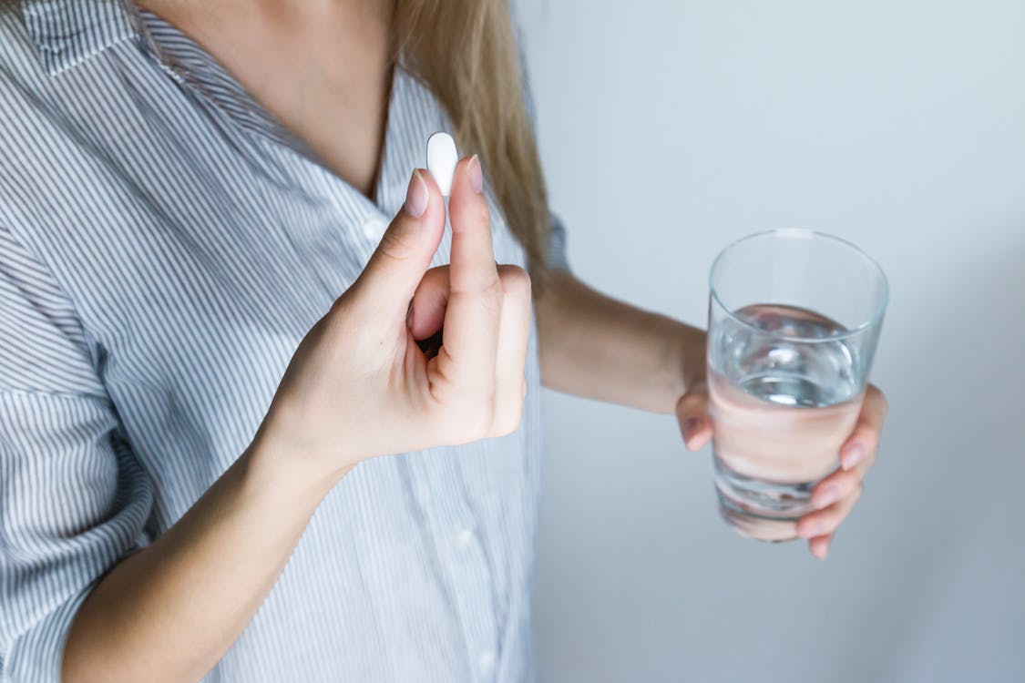 Senior woman holding a pill and a glass of water before taking daily medication