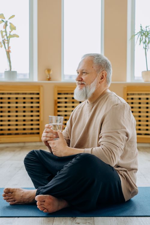 Elderly man holding a glass of water for hydration during warm weather at home