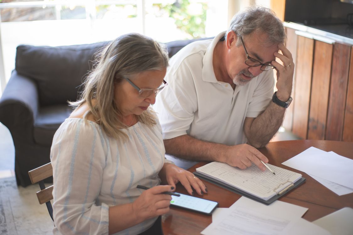 An elderly couple reviews assisted living facility disclosure documents at their kitchen table in Orange County