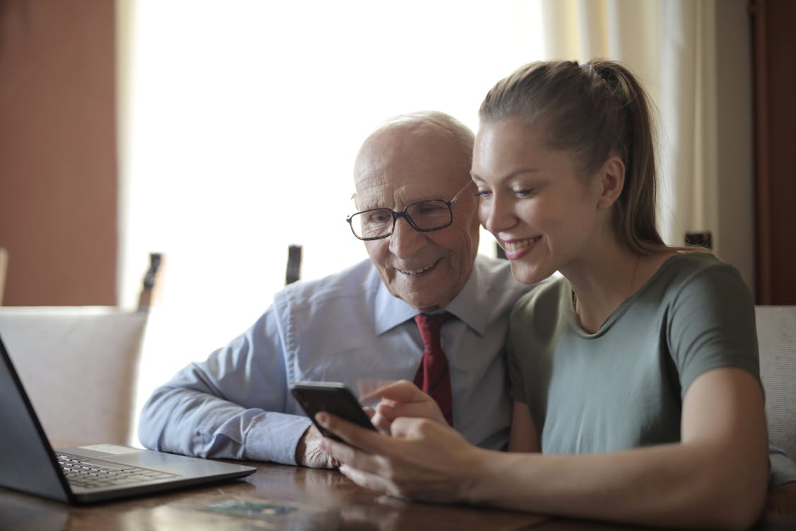 Young volunteer connecting with elderly man at home - Care Corps type interaction in Orange County