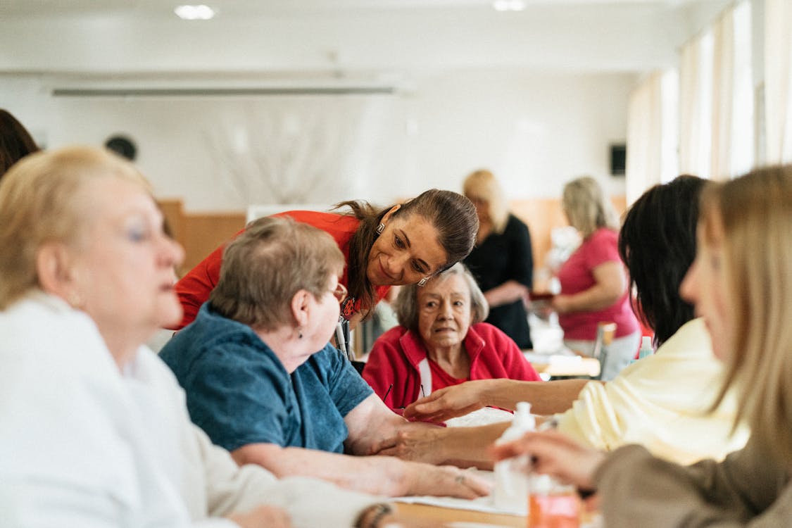 A professional caregiver sits with a group of Orange County seniors, offering the personalized attention that assisted living facilities cannot always provide