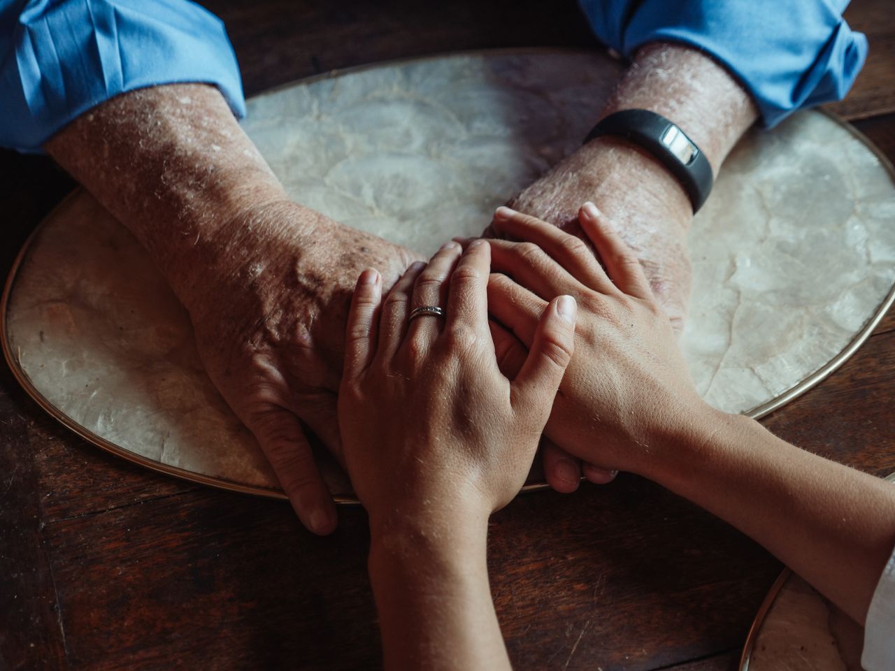 A younger person's hands holding an elderly person's hands &mdash; in-home care protected in the 2026-27 budget