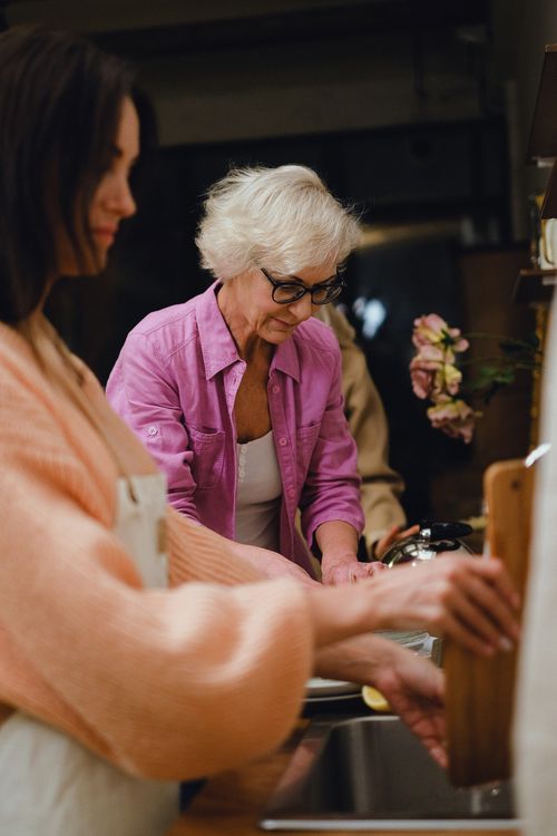 Family caregiver supporting elderly mother with daily tasks in Orange County kitchen