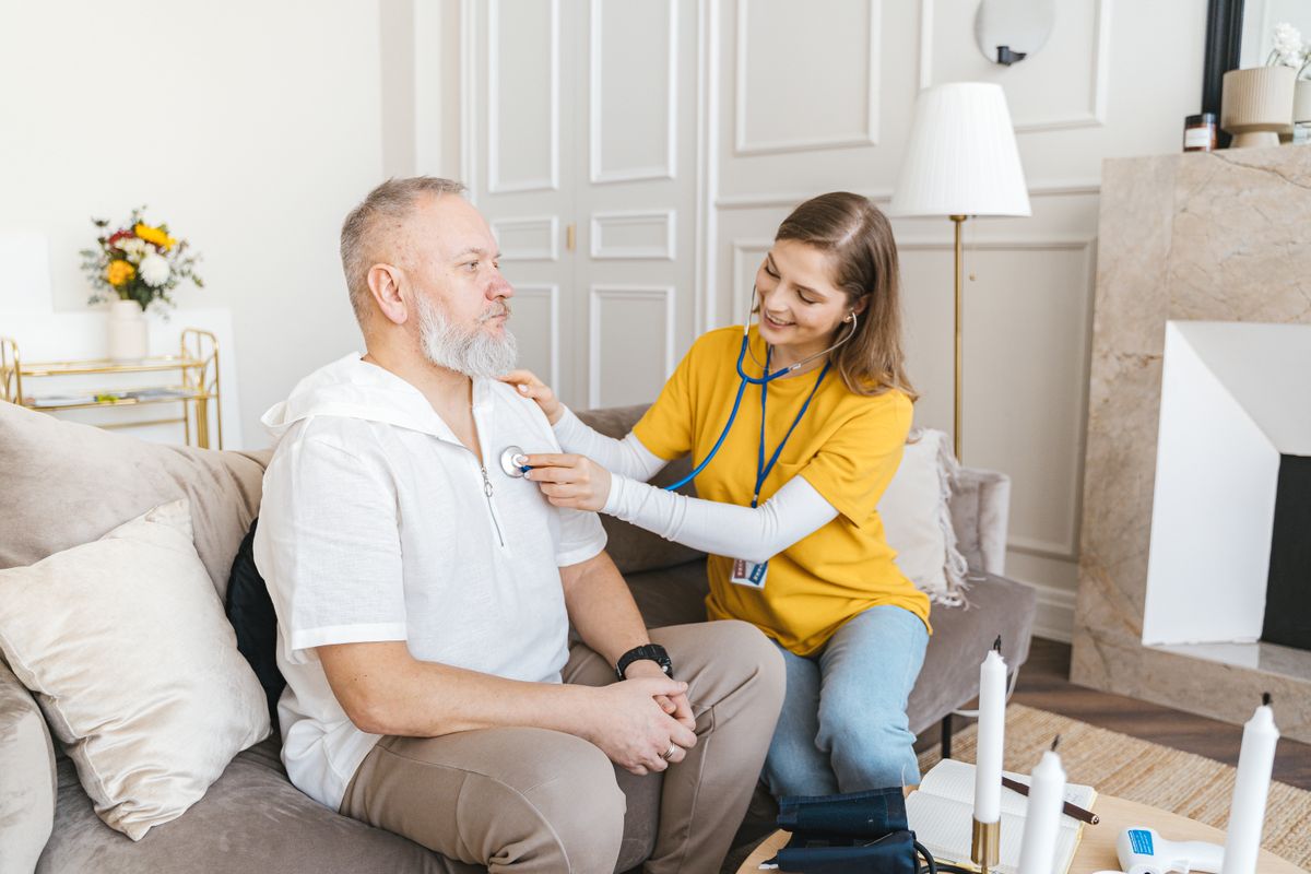 A caregiver performing a wellness check on a senior man at home during an Orange County heat advisory