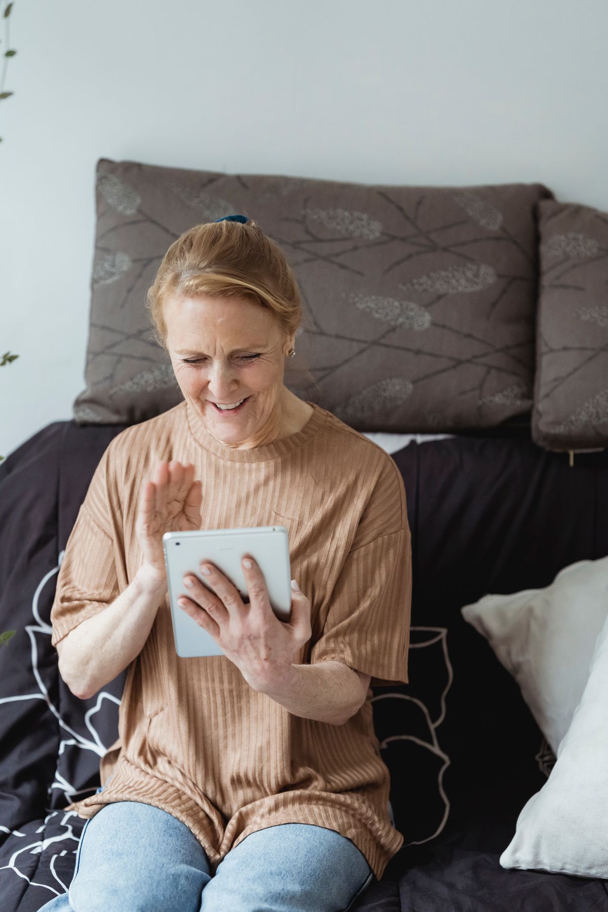 An older woman smiling during a video call check-in from home