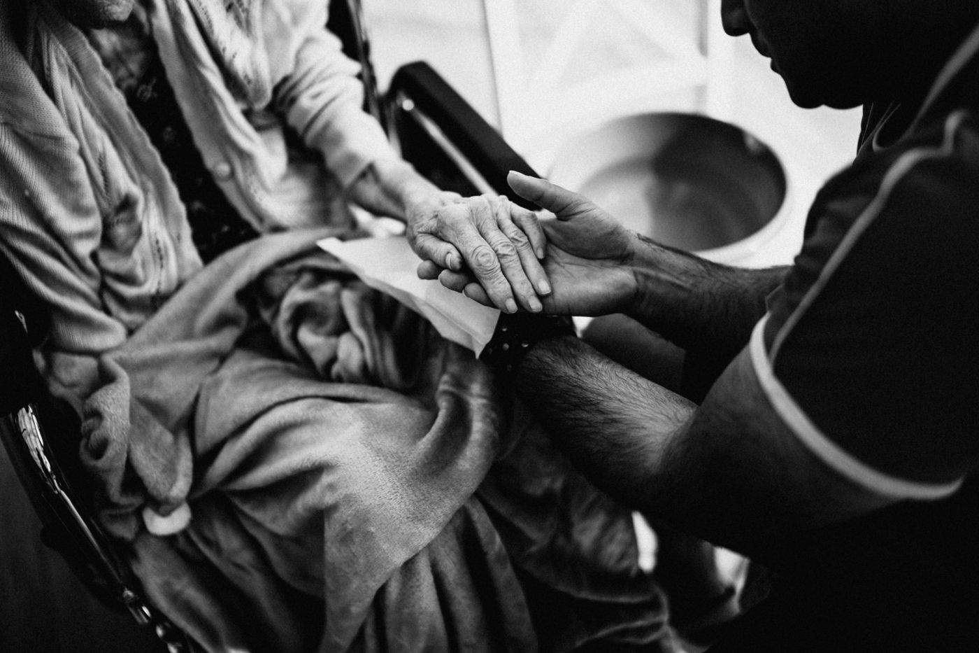 A home caregiver gently holding the hand of an elderly client