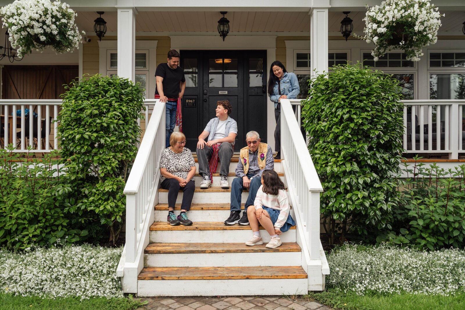 Multigenerational family gathered on the front porch steps of their Orange County home