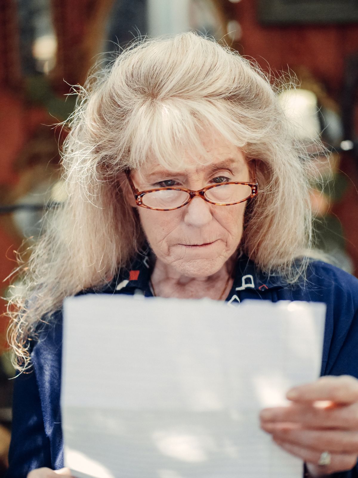 Older woman with glasses carefully reading a Medi-Cal notice at home
