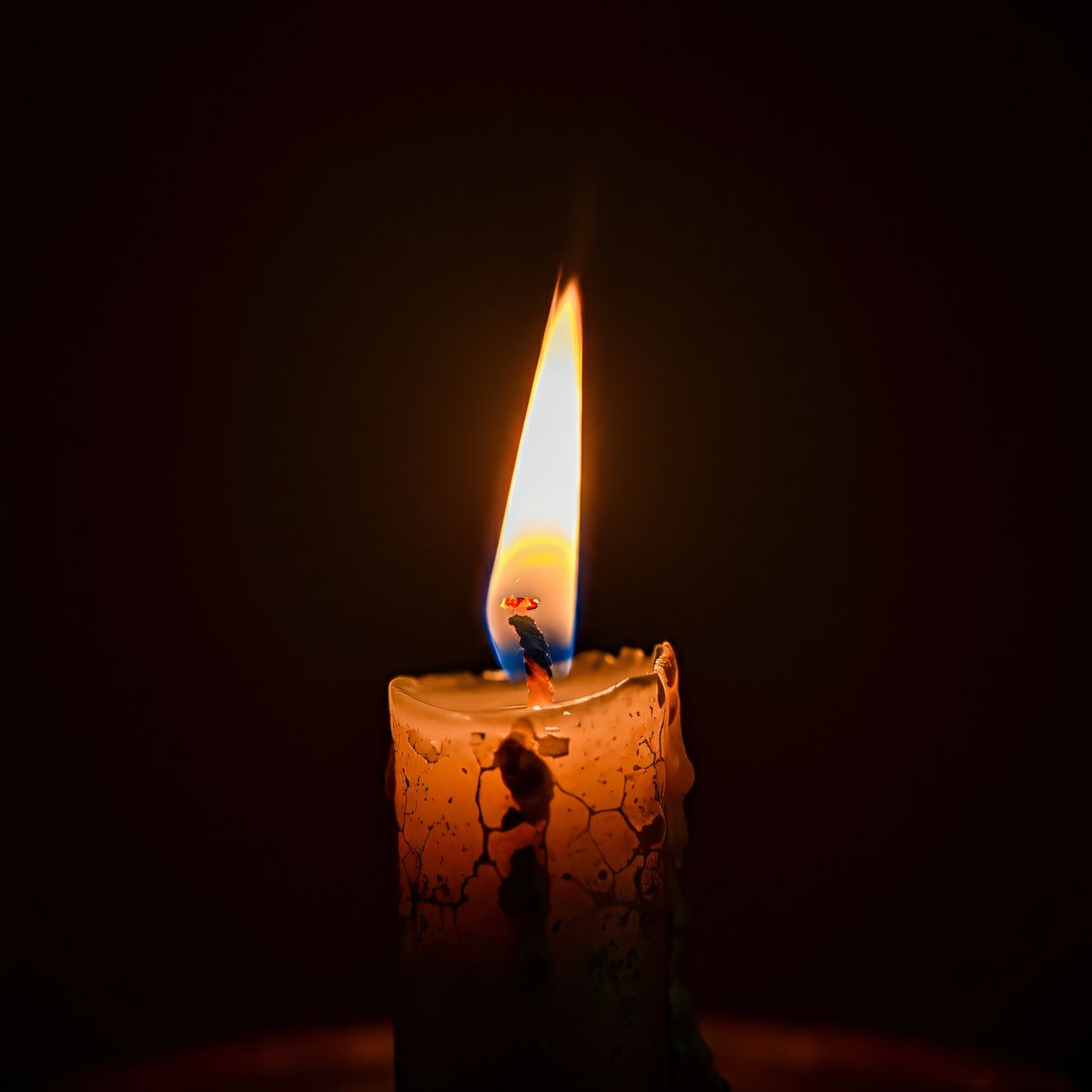 A single lit candle providing light in a dark room during a power outage
