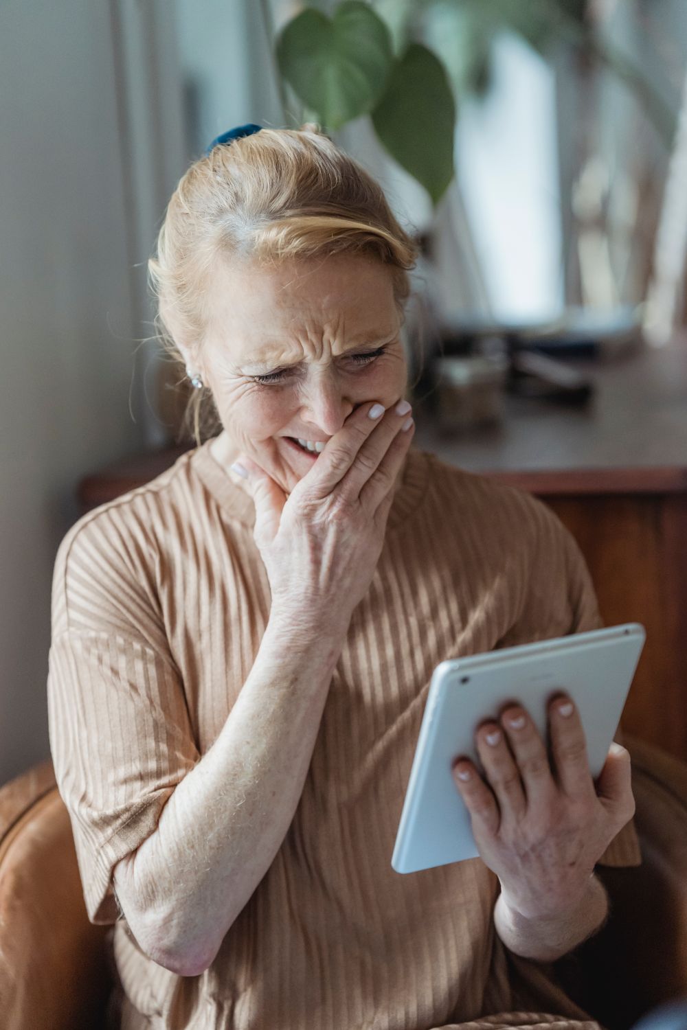 Senior in Orange County smiling while video calling family during a summer trip respite care arrangement
