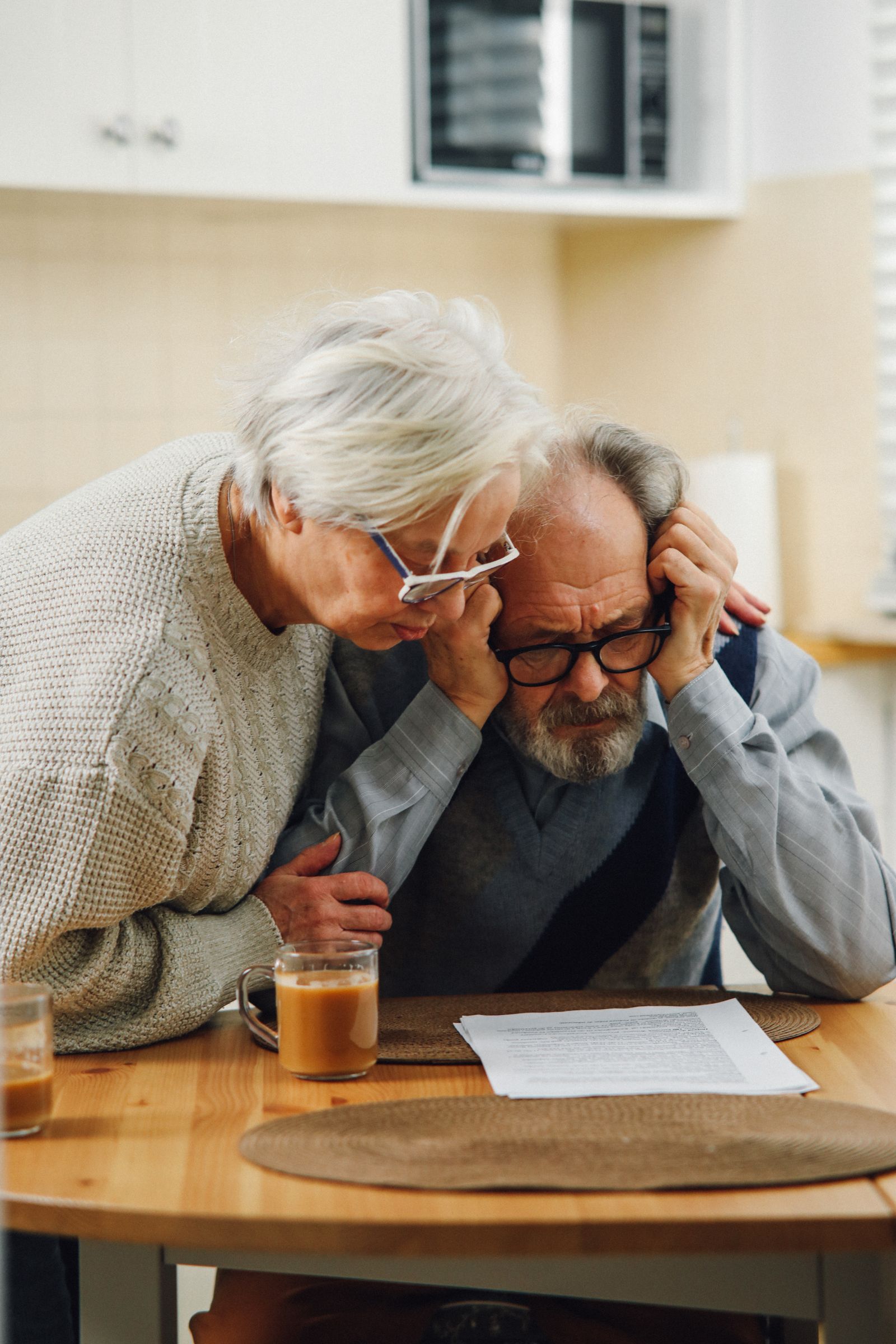 A worried senior couple reviews a document together at their kitchen table