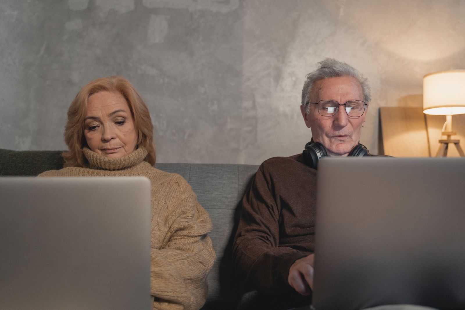 A senior couple sits together reviewing plan options on their laptops at home