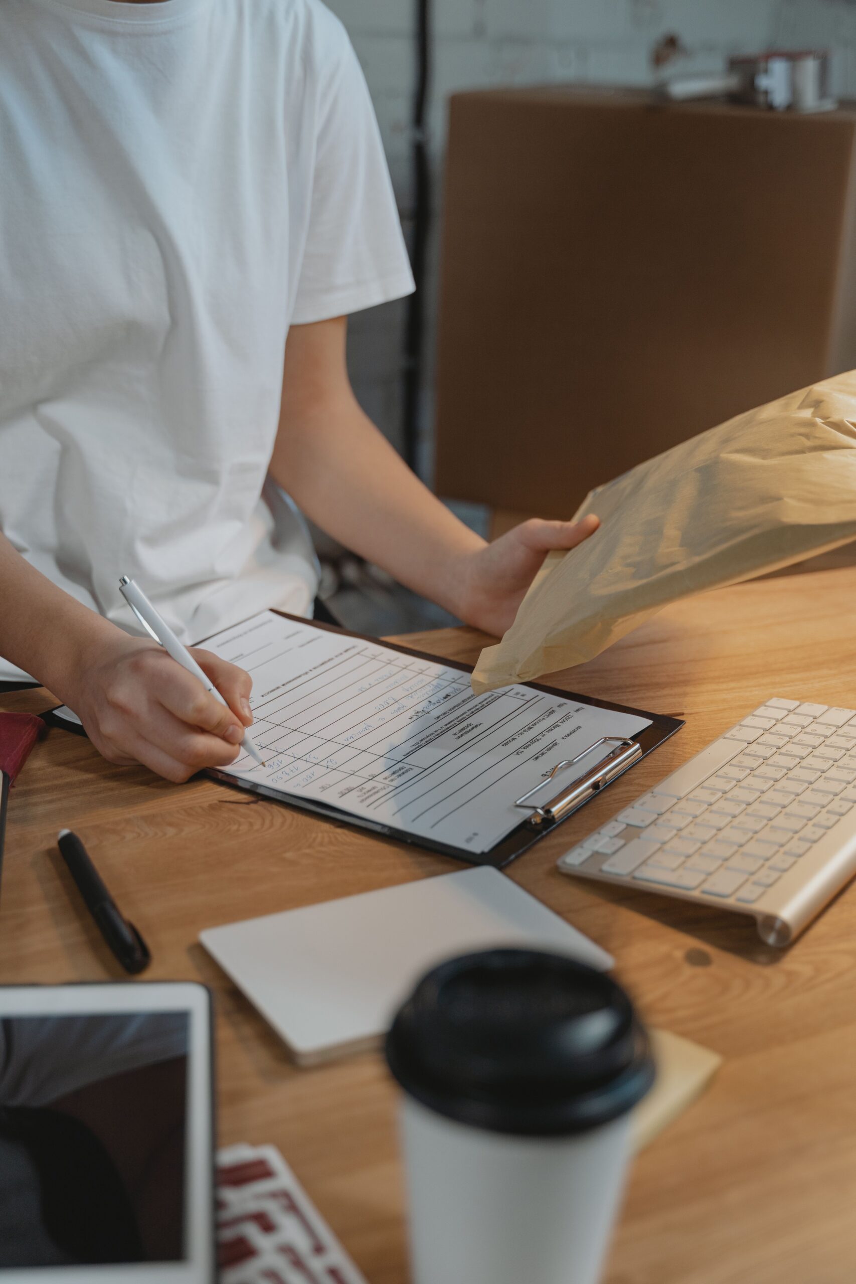 Hands filling out a paperwork form on a clipboard at a desk