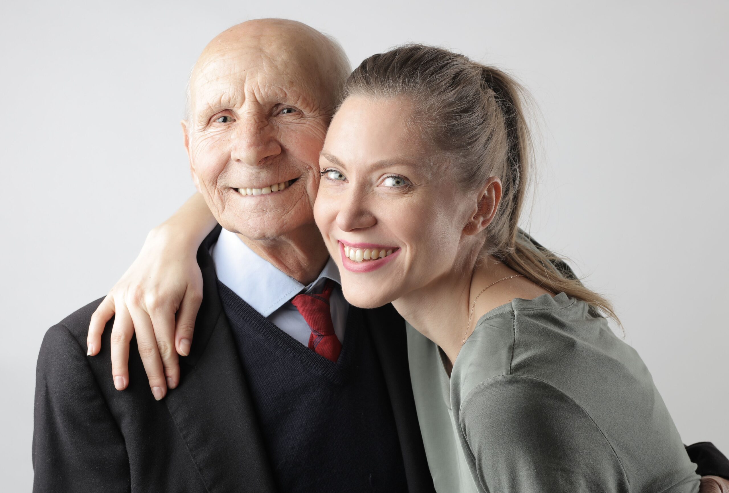 Senior father embracing his adult daughter, representing family caregiving relationships