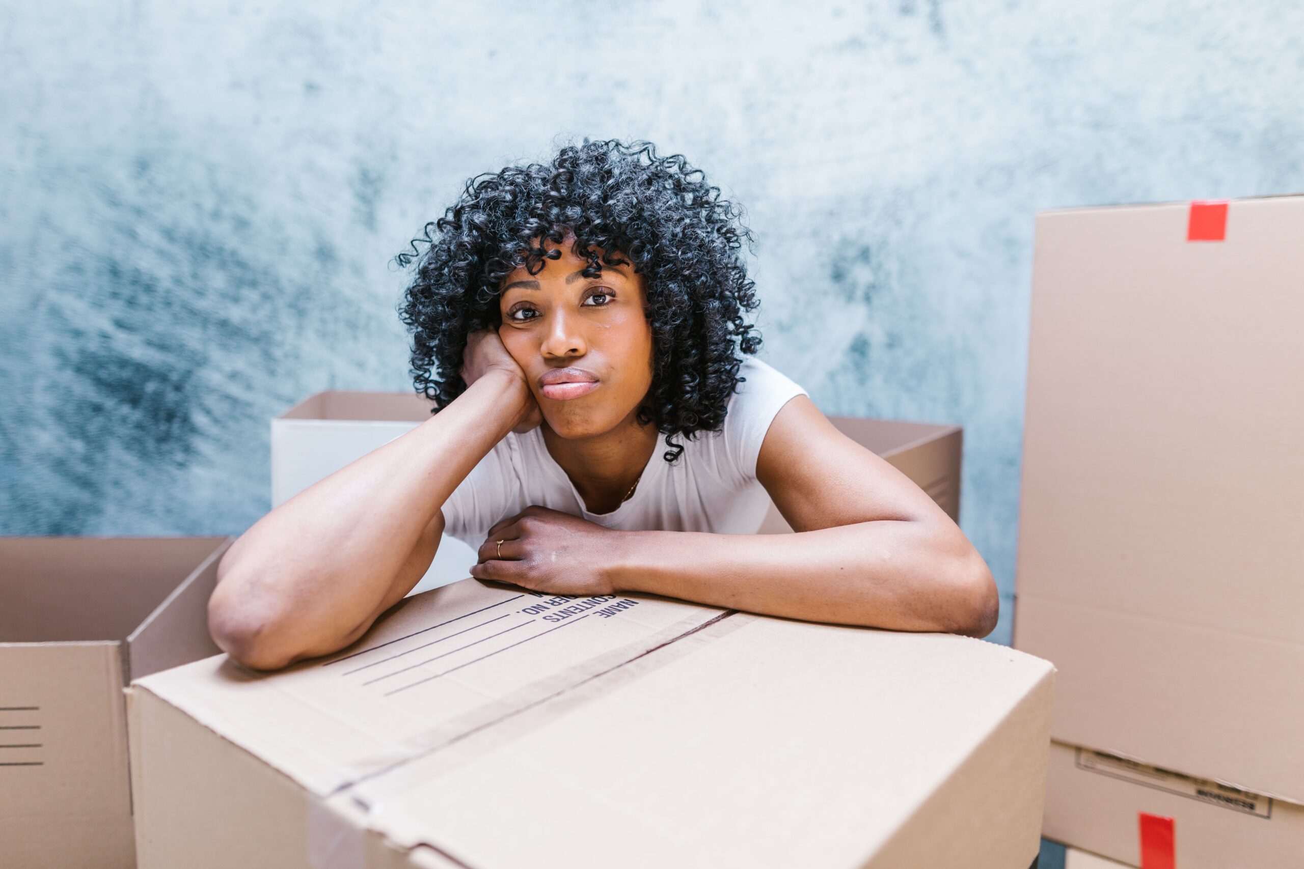A woman resting against moving boxes while packing to relocate