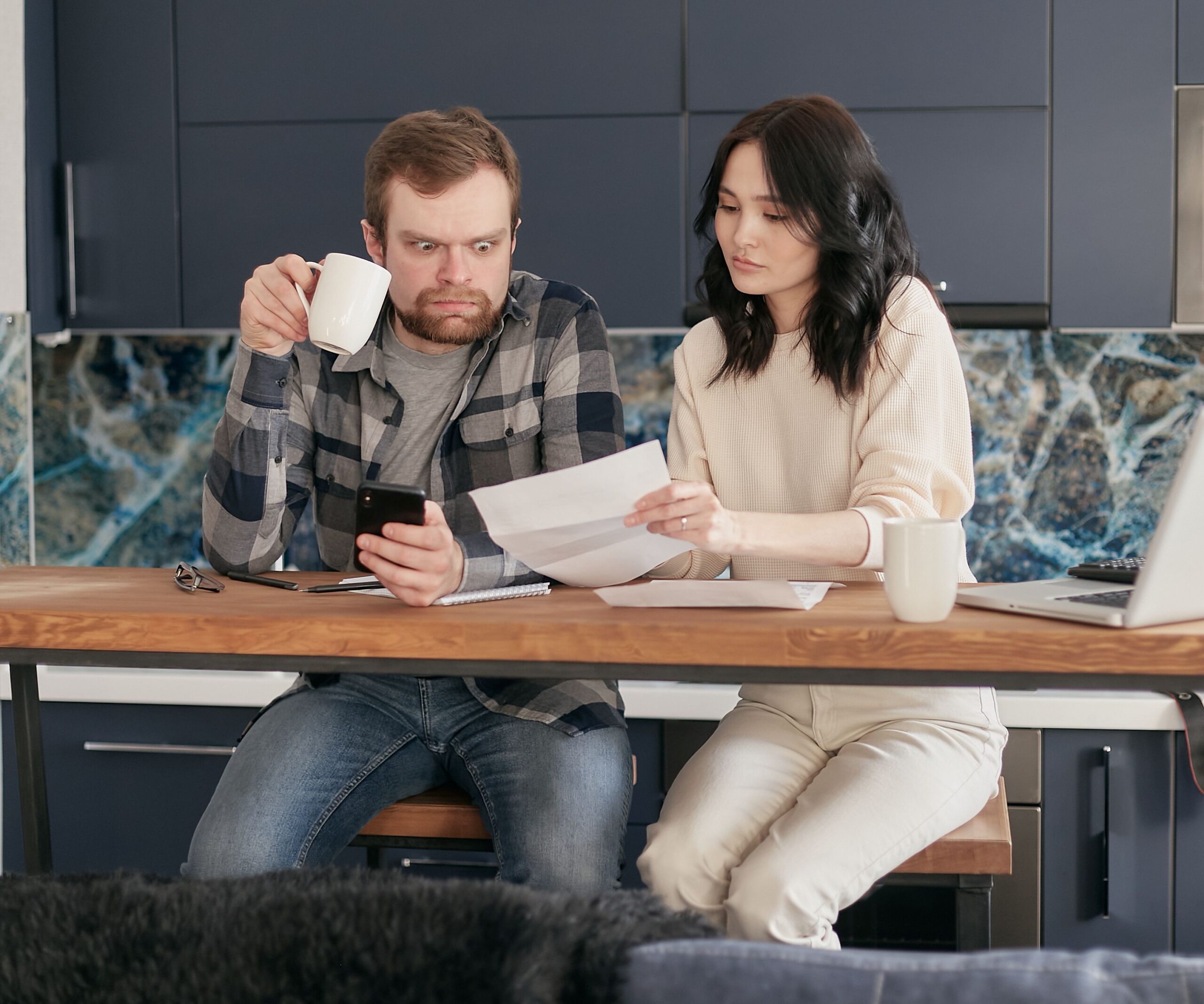 A couple reviewing financial paperwork together at their kitchen table, looking concerned