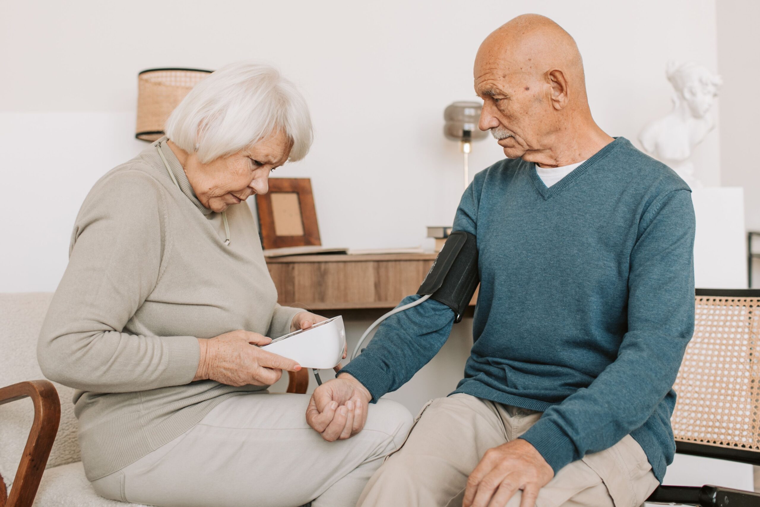 An elderly couple checking blood pressure together at home using a home monitor