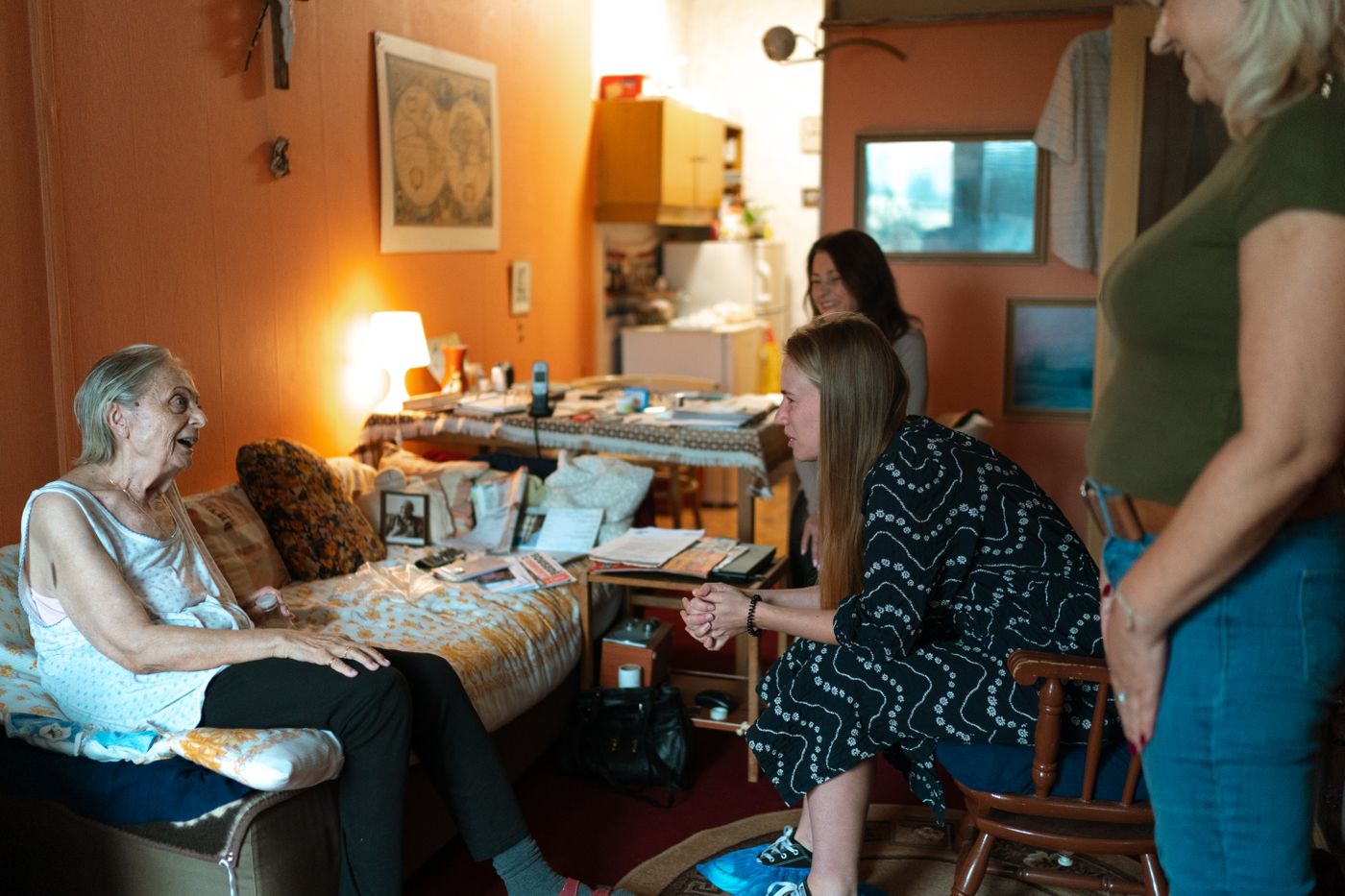 Family members and a visitor talking with an older woman in her living room