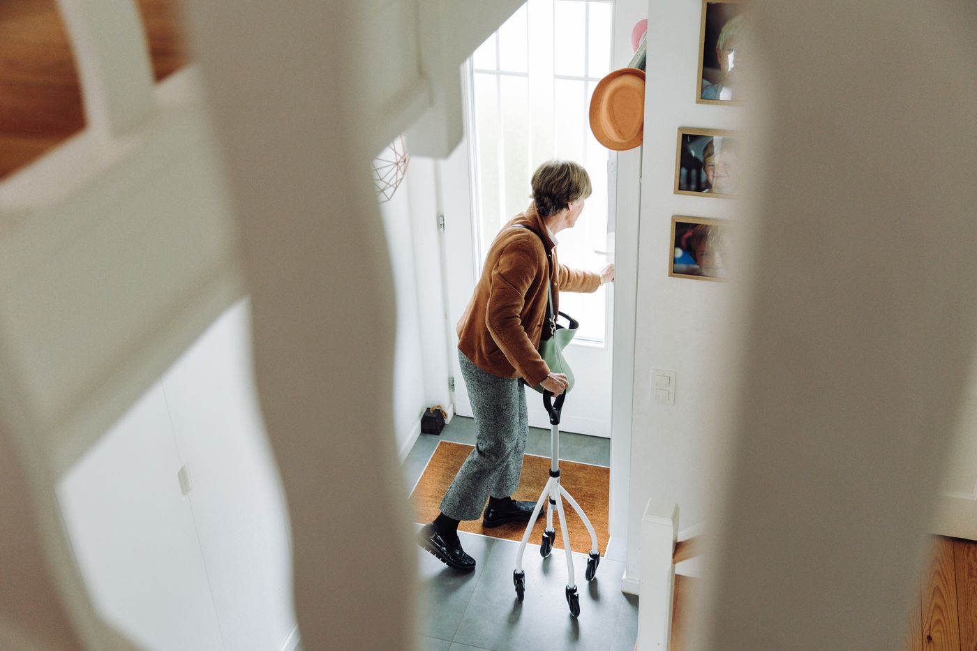 Older adult using a walker at the front door of a home, preparing to go outside