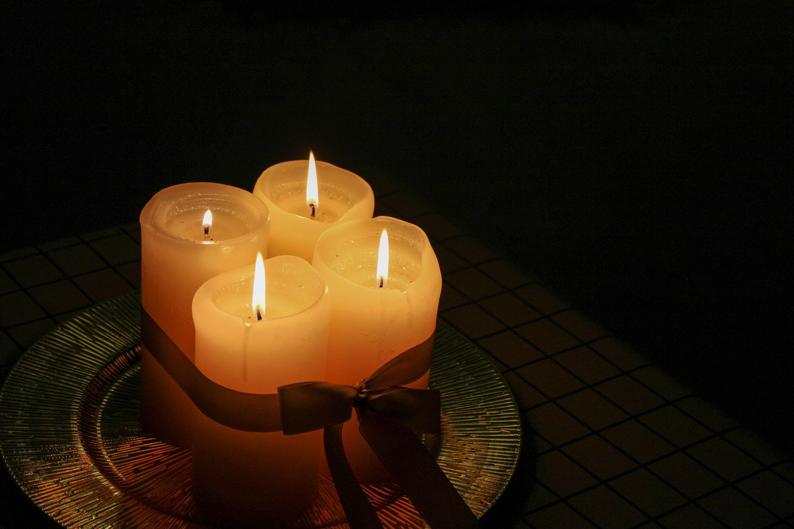 Lit candles burning on a glass plate in a darkened room