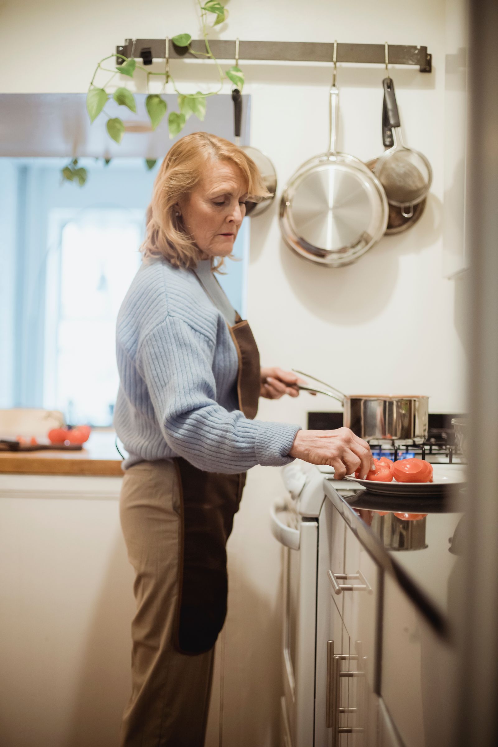 Older woman cooking at a stove with pots on the burners