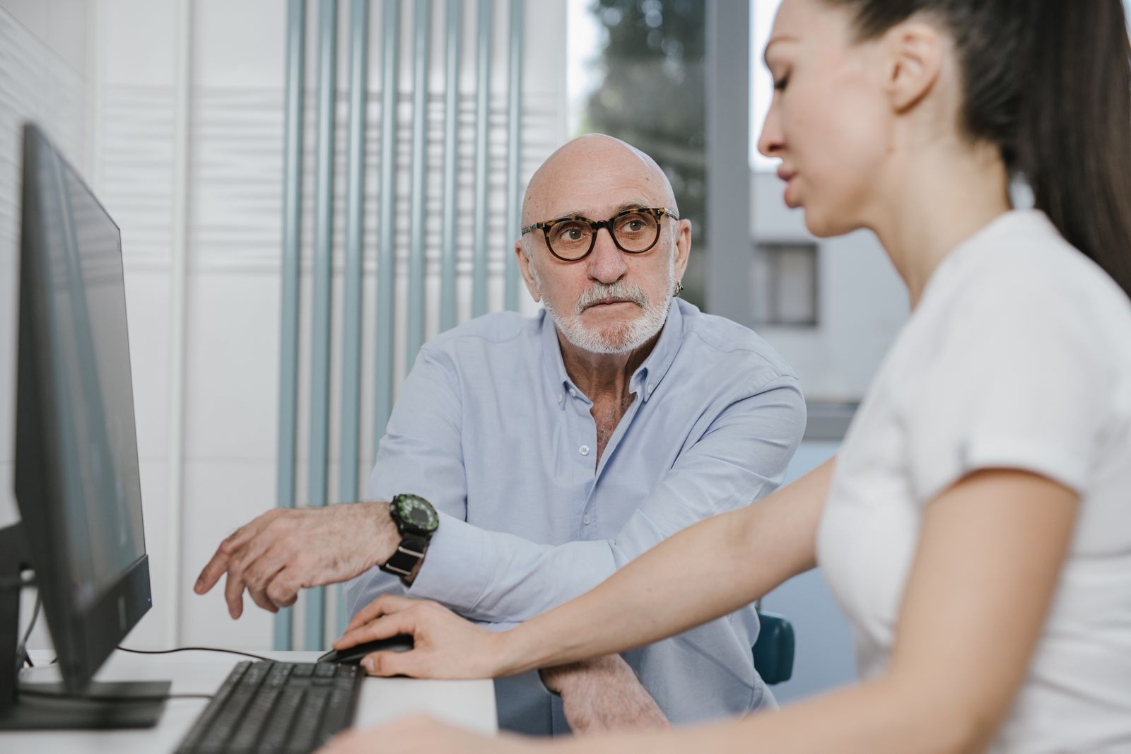 Senior man reviewing his Medicare Advantage plan's provider network status on a computer screen with help from a family member