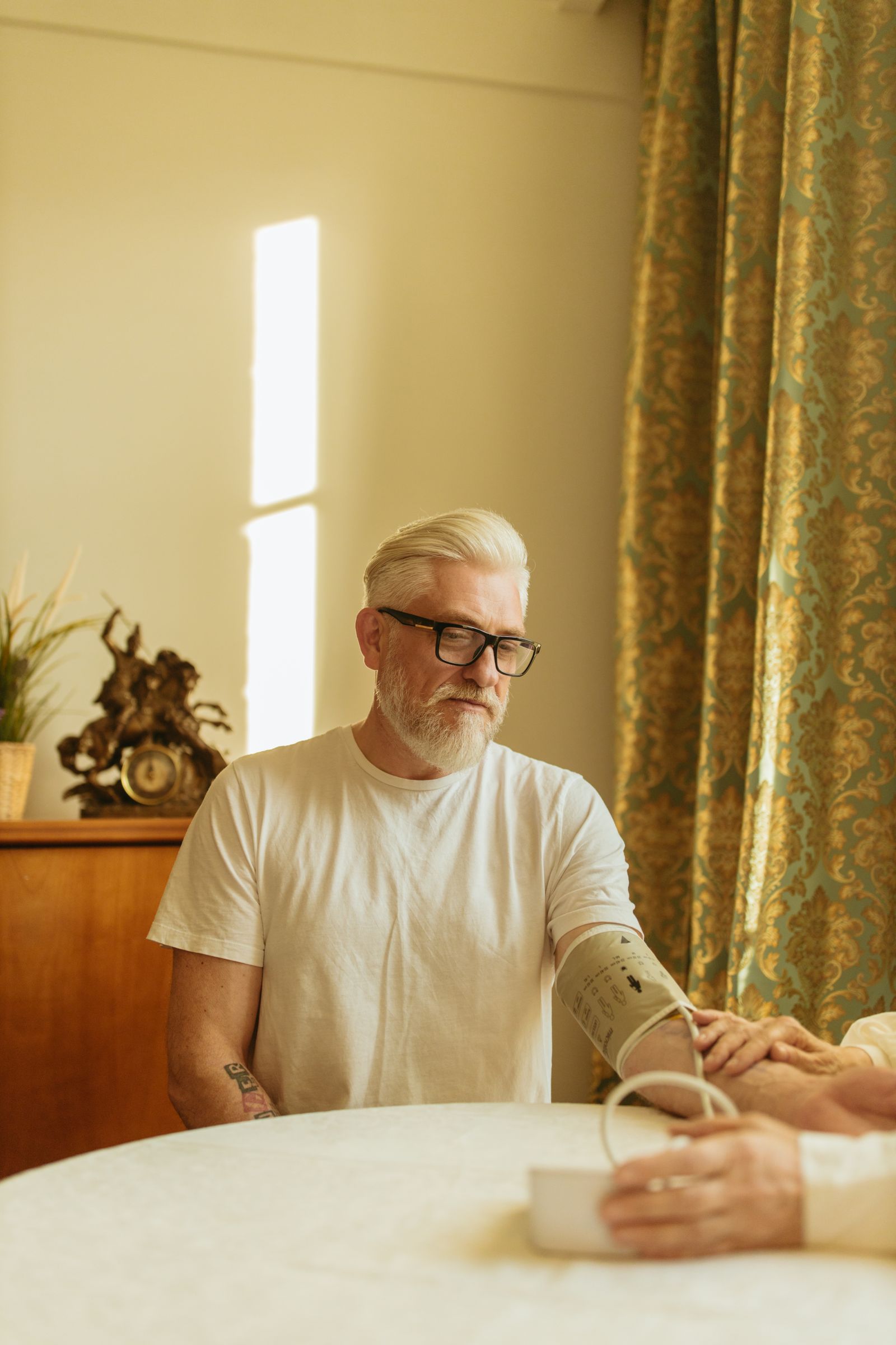 Senior man checking his blood pressure at home during a home health visit