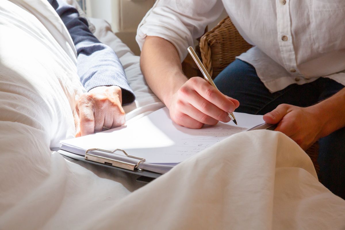 Hands completing a clipboard form together at a home dining table