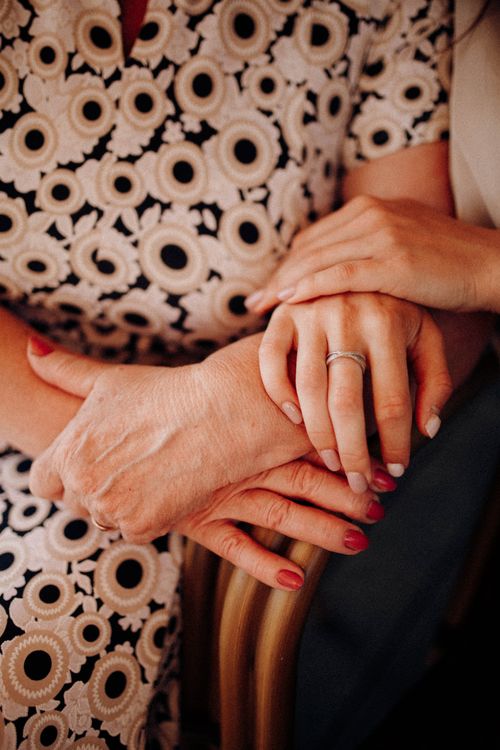 Close-up of an adult's hands resting supportively over an older family member's hands