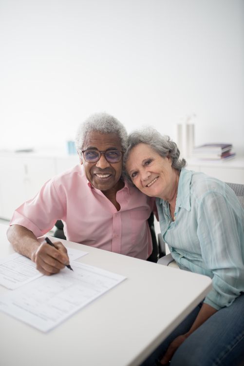 Senior couple smiling while signing a legal planning document together