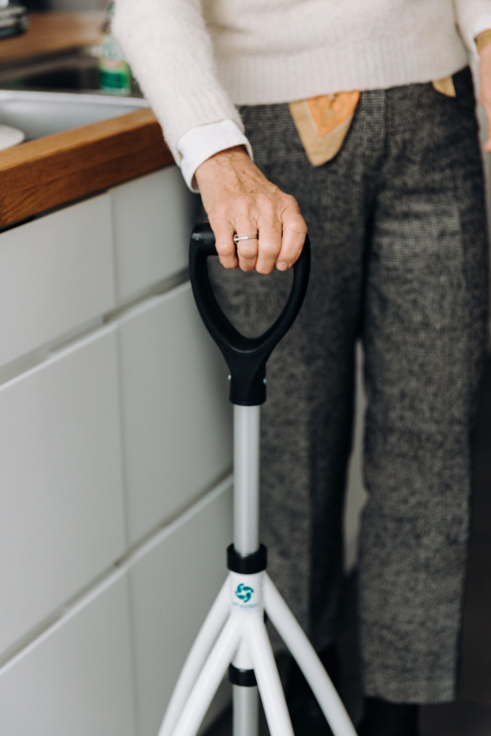 Close-up of a hand gripping a mobility walker handle in a home kitchen
